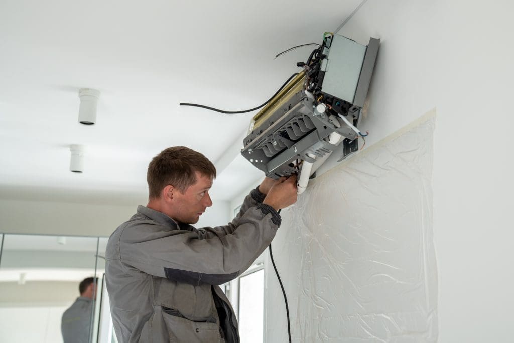 A service technician working on a mini-split installation in a new building