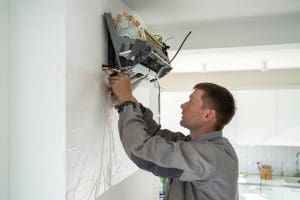 A maintenance worker looking at a mini-split system that has had the case removed, exposing the inner workings