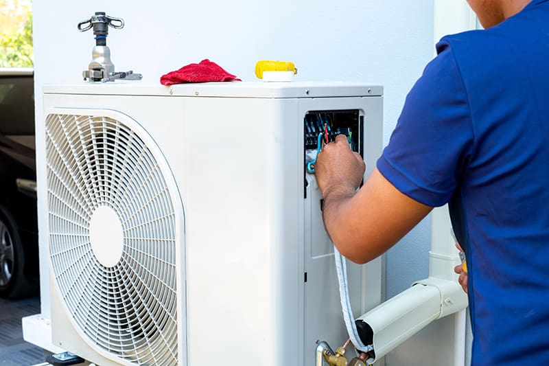 An HVAC tech working on an outdoor unit