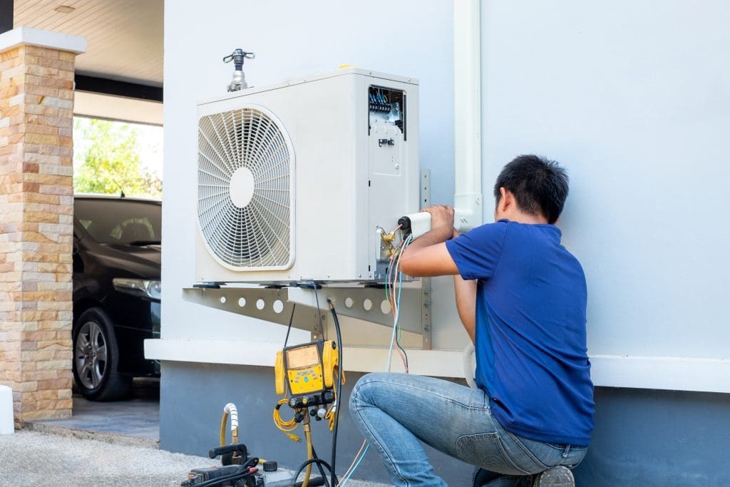 A maintenance worker checking an outdoor heating unit.