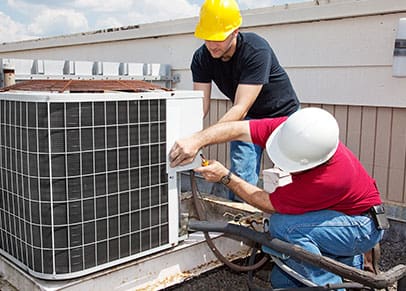Two men working on an industrial ac unit.