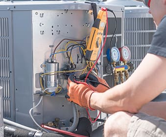 HVAC technician working on controls of air conditioner